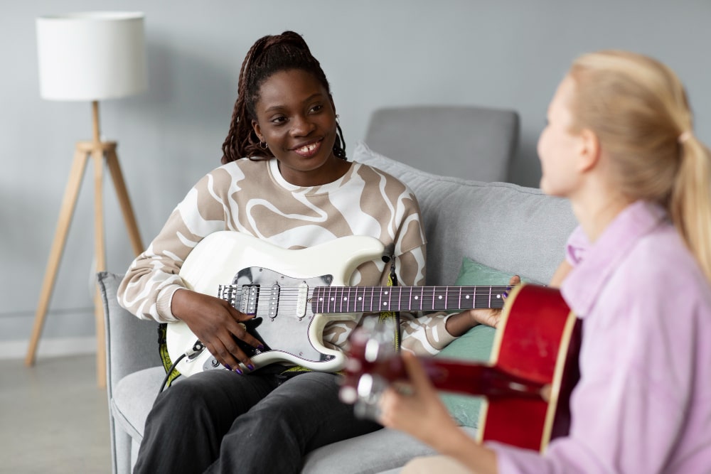 close-up-smiley-women-playing-guitar-home-min